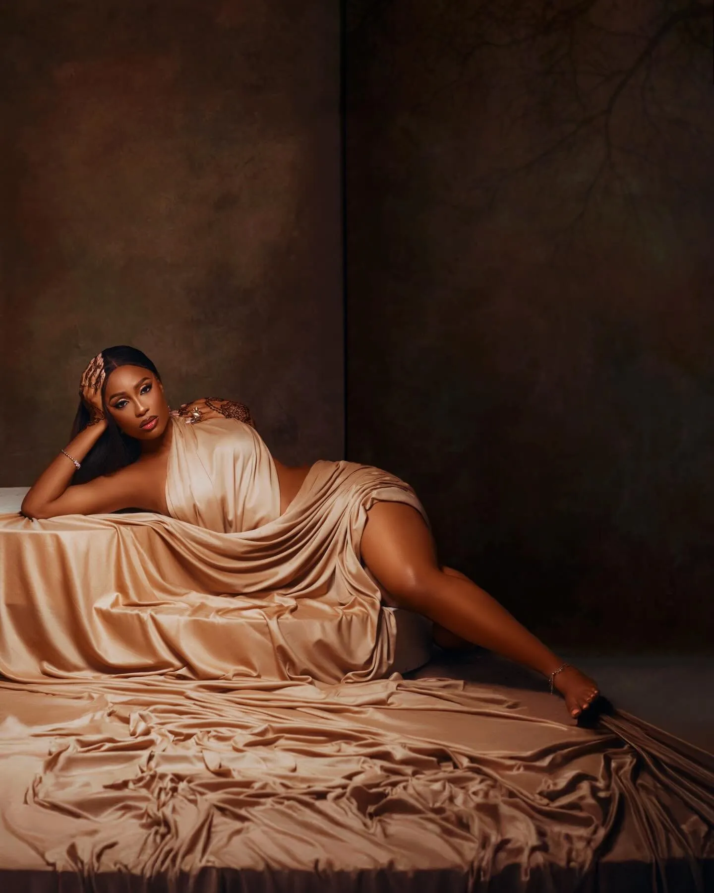 Woman reclining on folds of caramel silk
