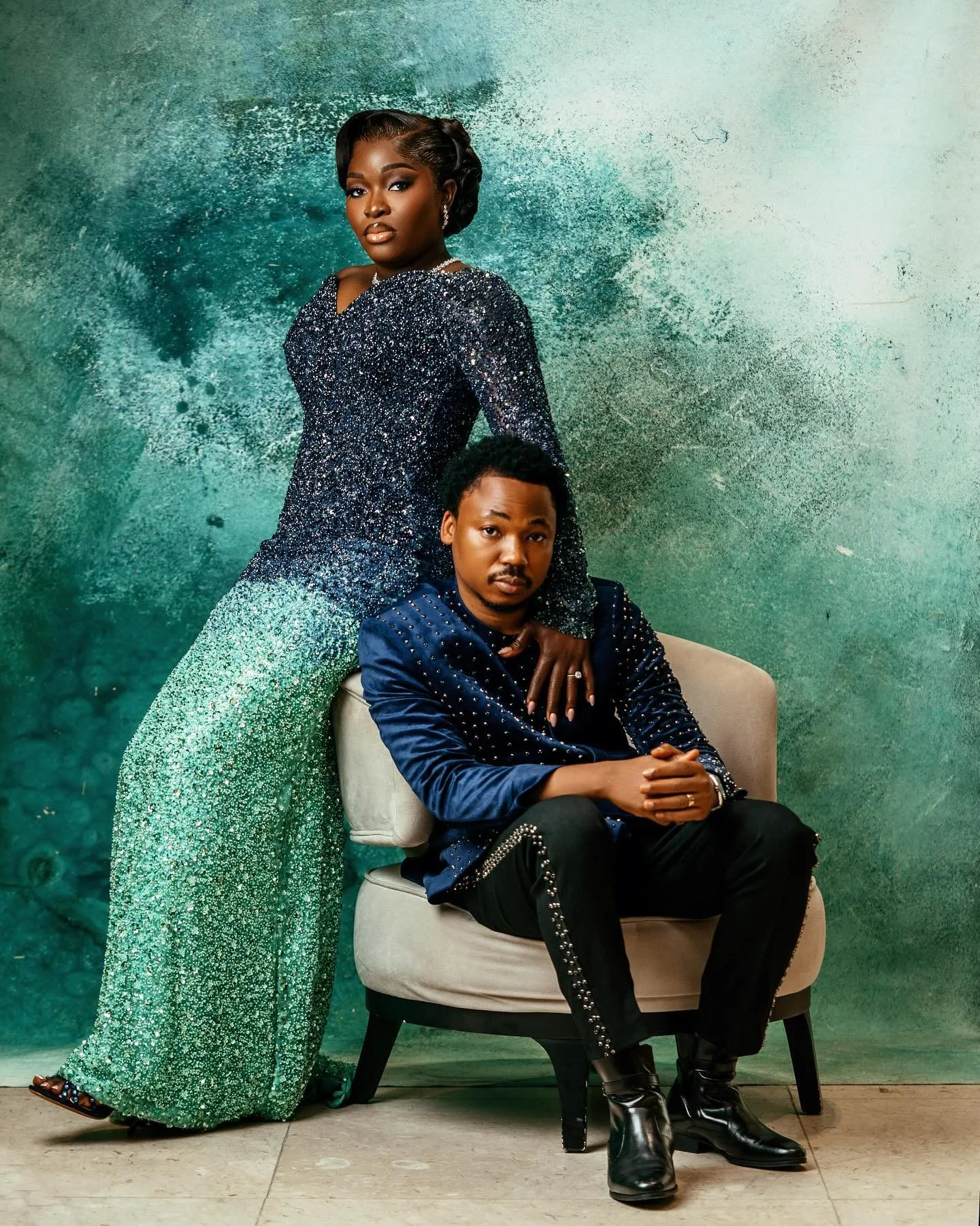 Groom seated in an armchair, bride standing beside him