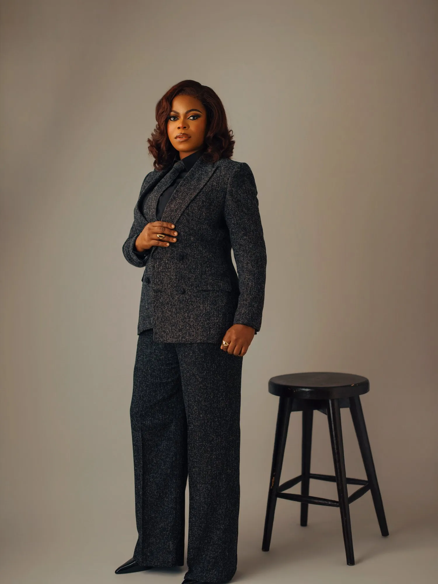 Woman standing in a tweed suit beside a bar stool