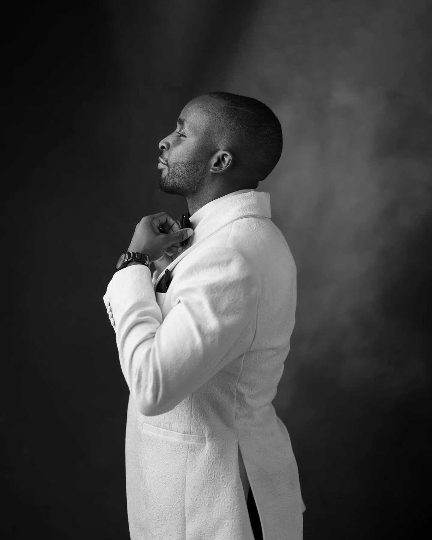 Black-and-white photo of the groom fastening his cufflink