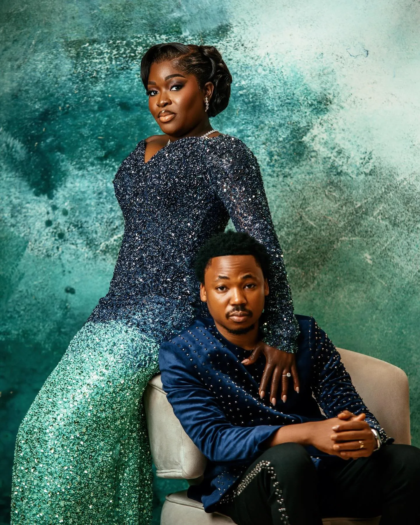 Bride perched on the arm of the chair, groom seated