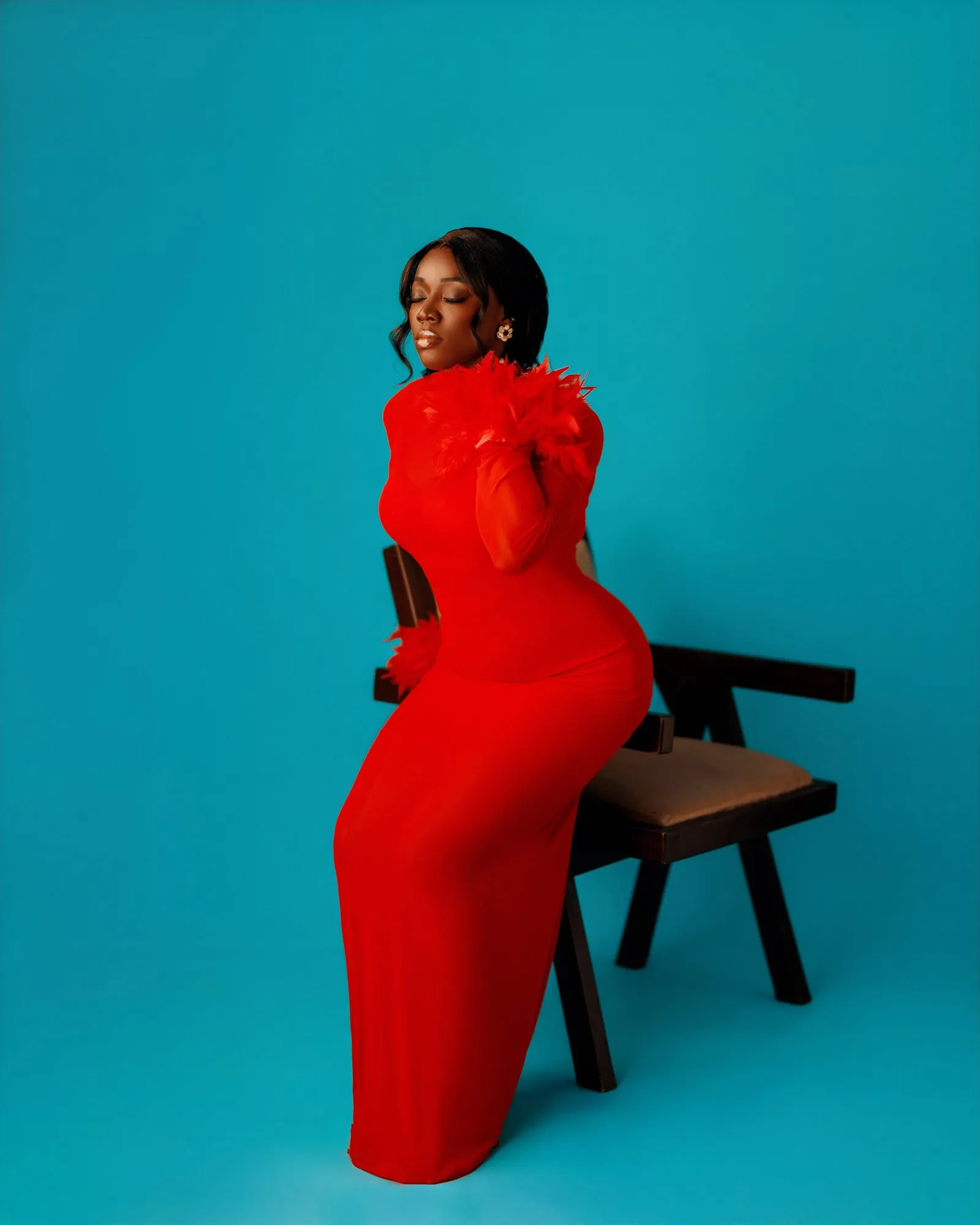 Woman in red perched on the edge of a wooden chair
