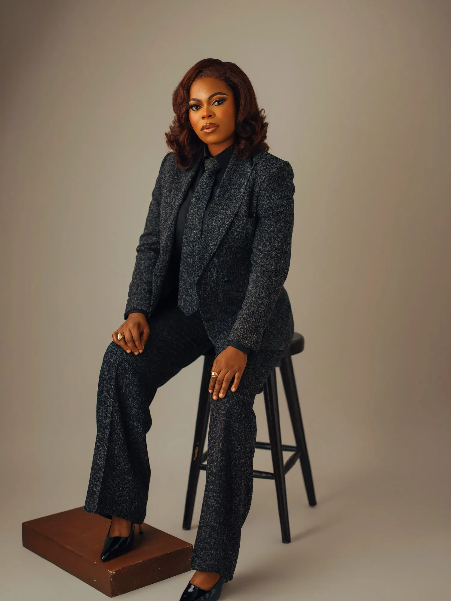 Woman perched on a stool with one foot on a wooden box