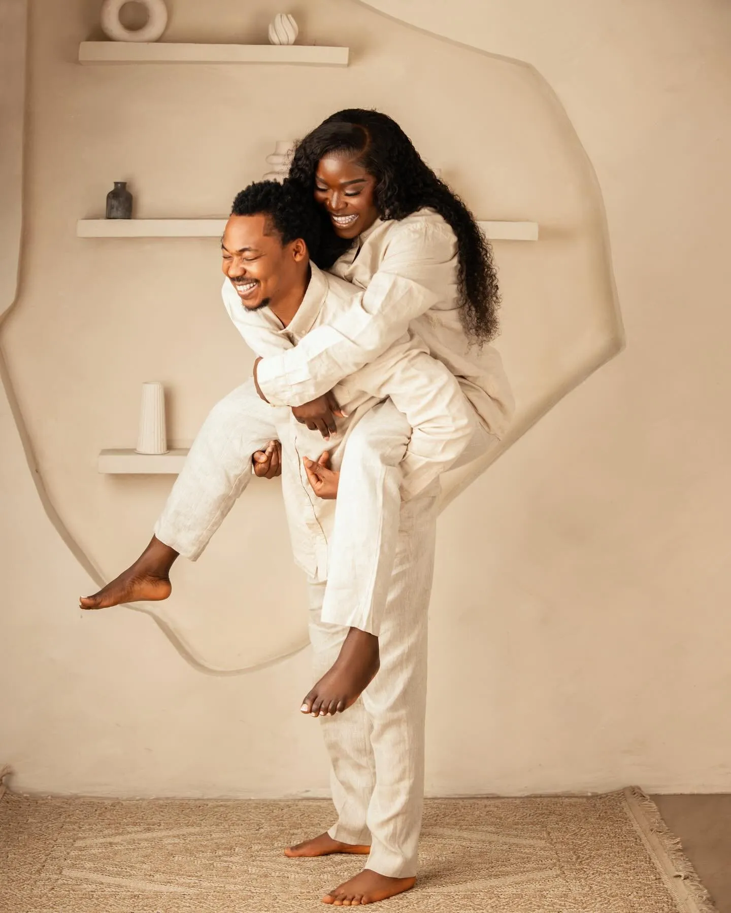 Groom giving the bride a piggyback in matching cream outfits