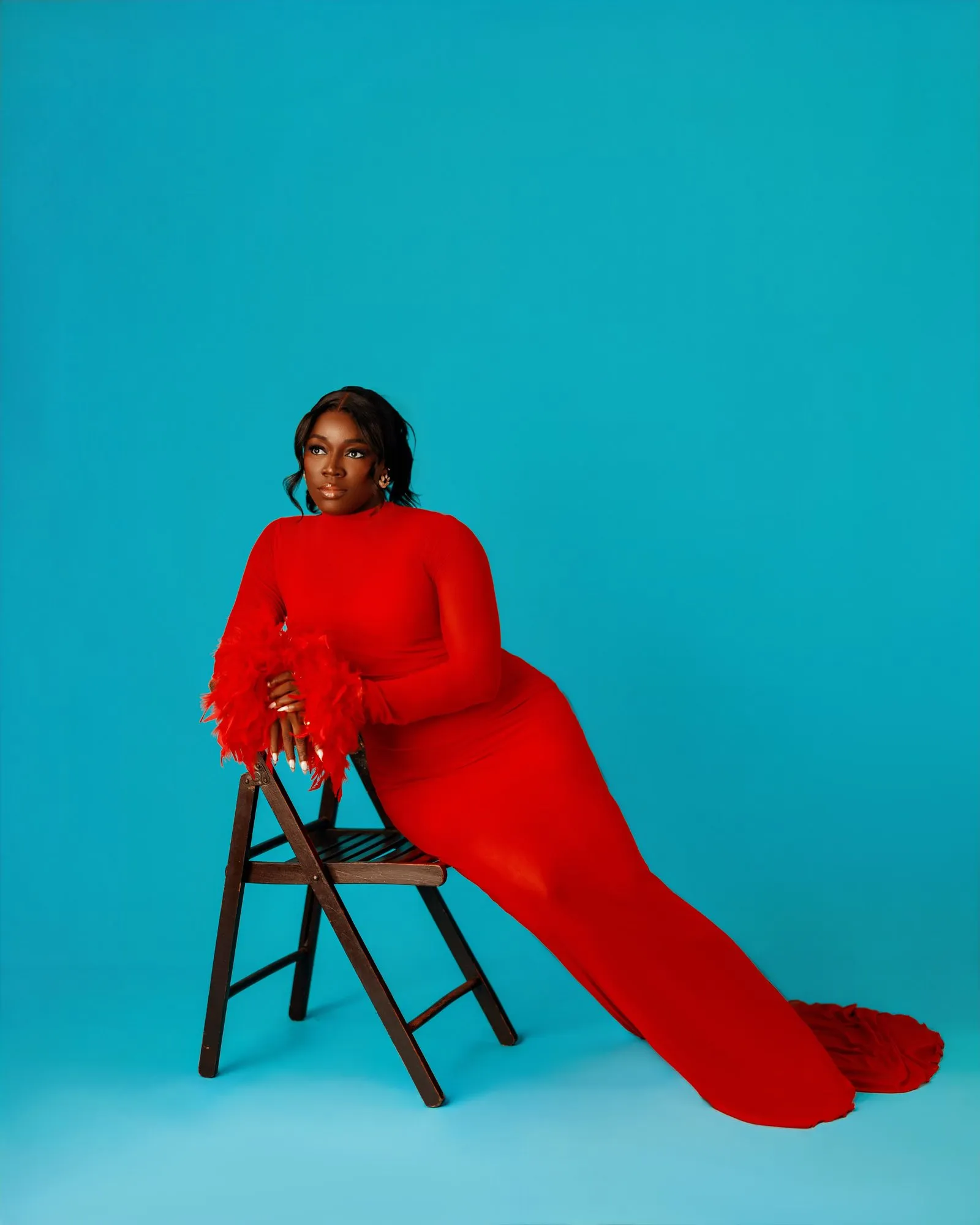 Woman in red seated low, her train swept to one side