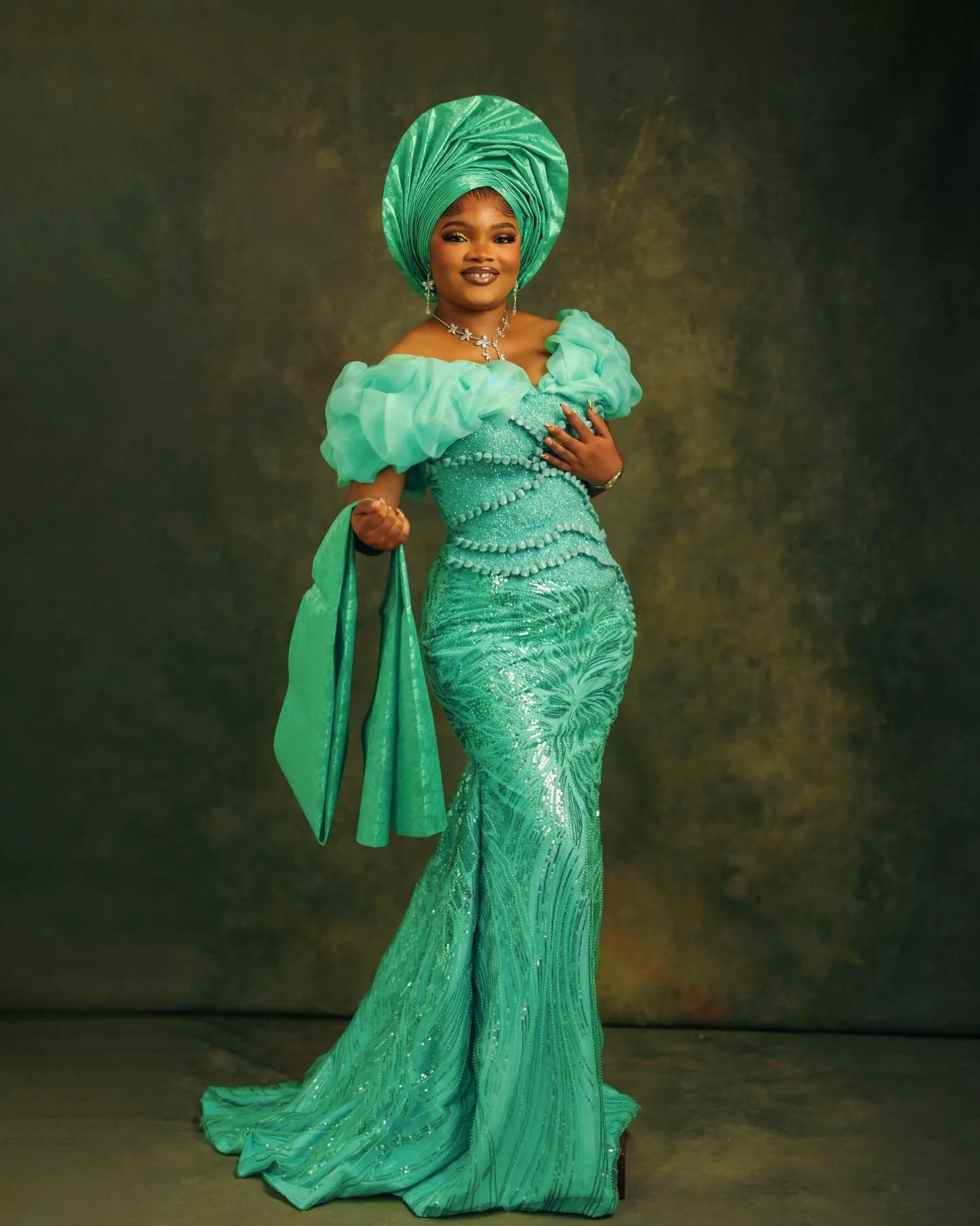 Full length in jade, holding her ipele