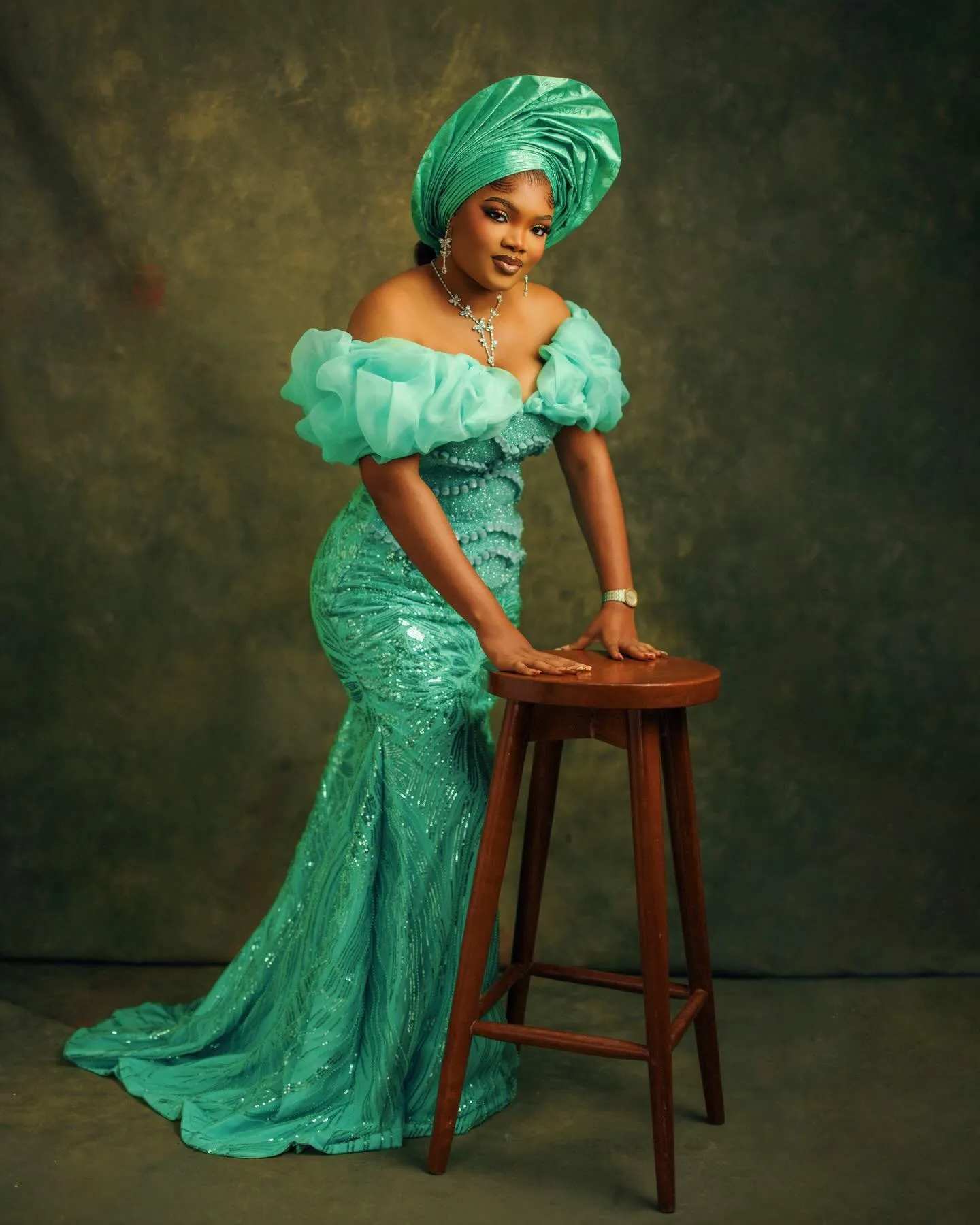 Woman in jade leaning on a wooden stool