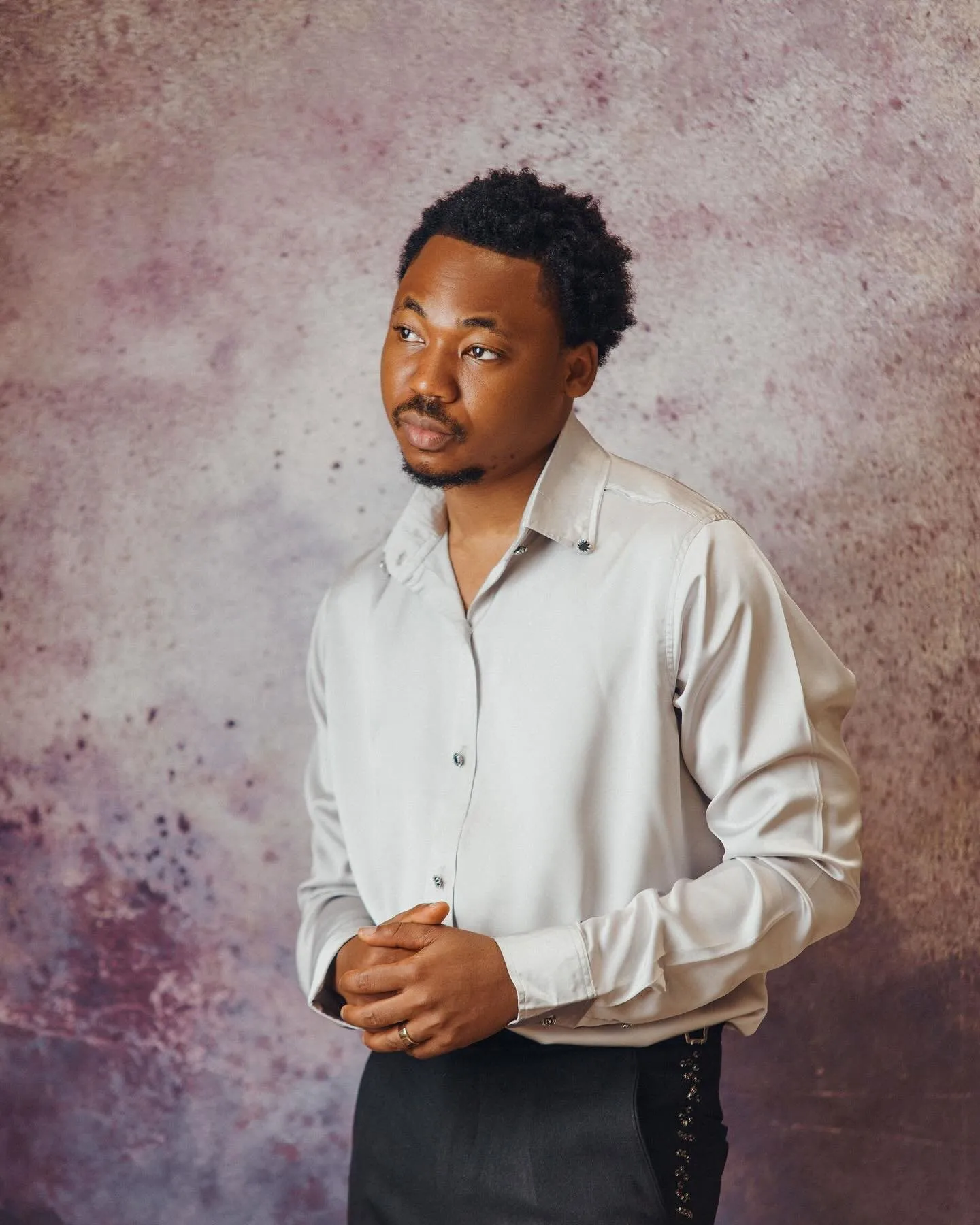 Groom in a white shirt against a mauve backdrop