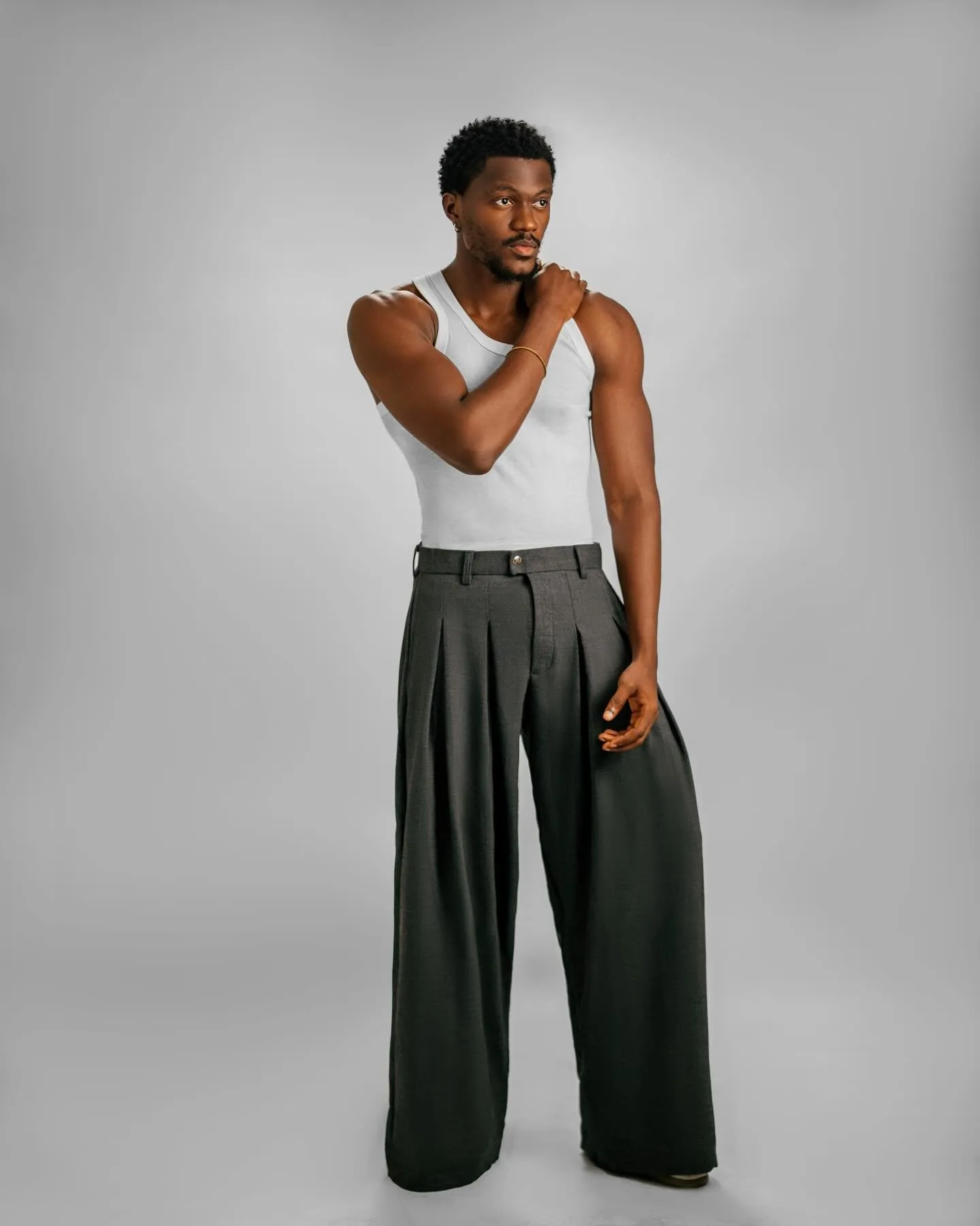 Desanmi in a white vest and wide trousers on a grey studio backdrop