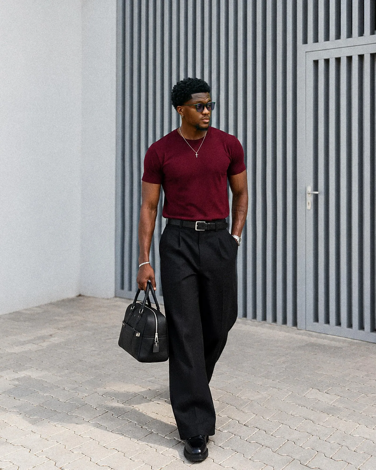Desanmi walking in a burgundy tee and black trousers